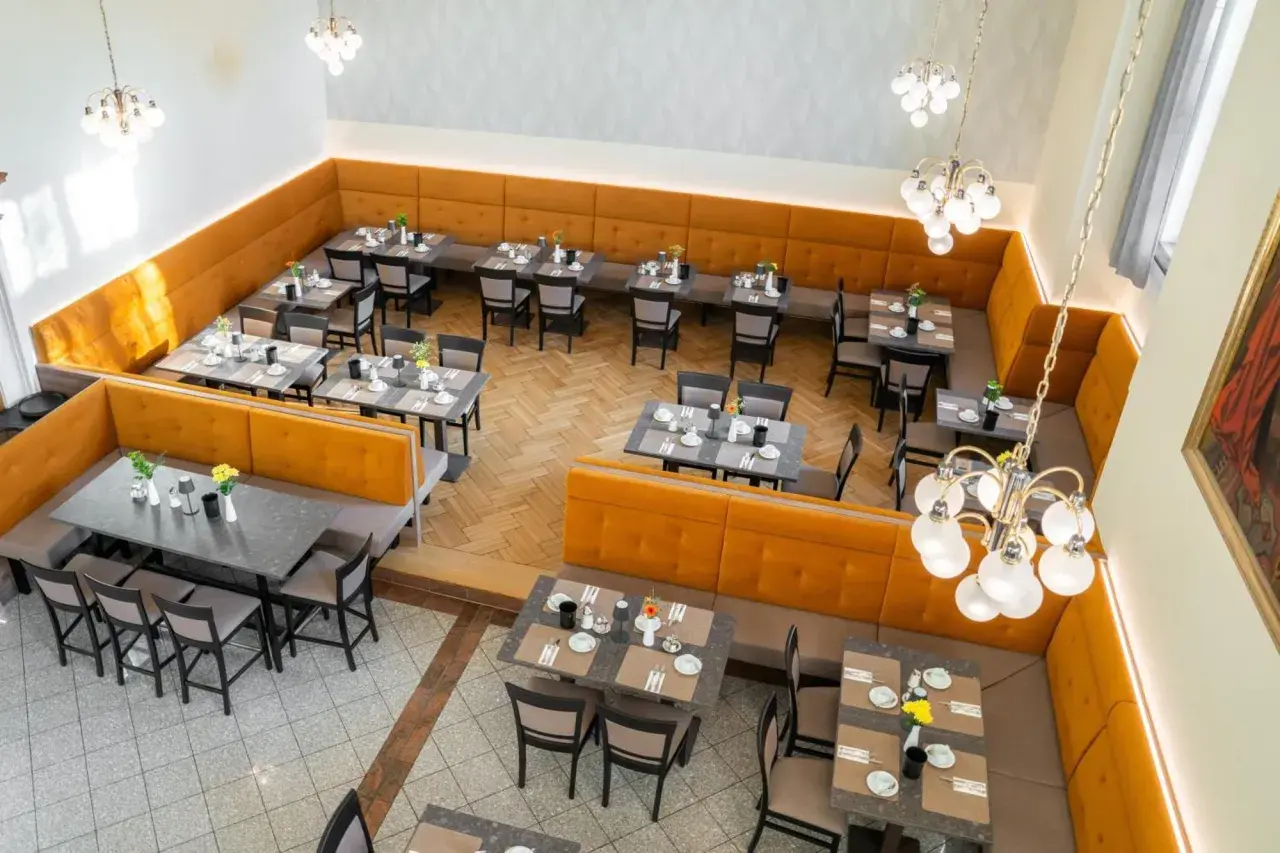 Gemütliche Tische mit Blumenarrangements im Speisesaal des **Pallottiner Salzburg**.