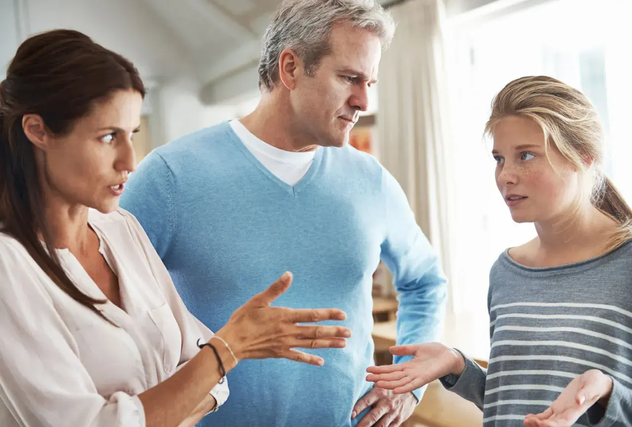 Ein ernstes Gespräch zwischen Eltern und Teenager. Die Mutter gestikuliert, der Vater schaut besorgt. Ein typischer **Streit in der Familie**.