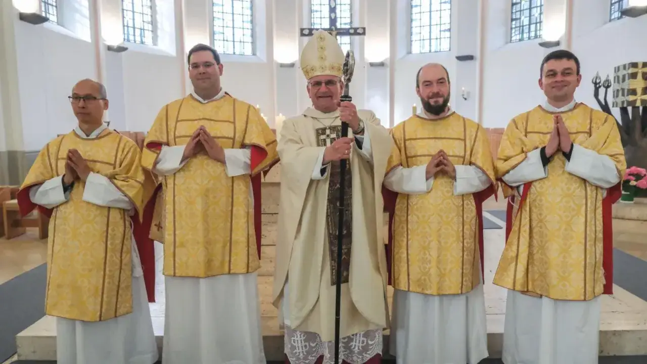 Johannes Roggendorf und vier Geistliche in festlicher Kleidung stehen in einer Kirche.