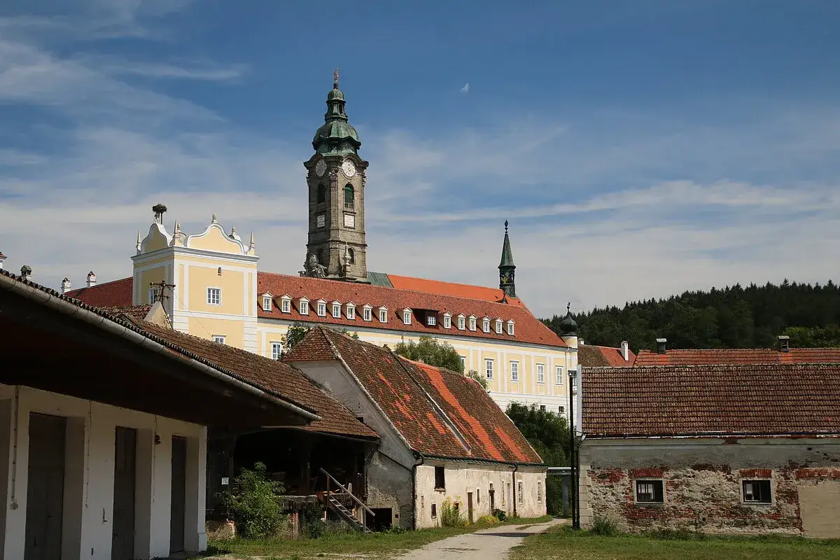 Das Stift Zwettl, ein imposantes Kloster mit markantem Turm, ragt hinter alten Wirtschaftsgeb&auml;uden auf.