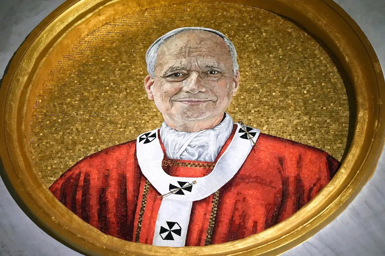 Mosaikbild von Papst Leo, der in seiner roten Soutane und dem weißen Zingulum mit Kreuzen lächelt.