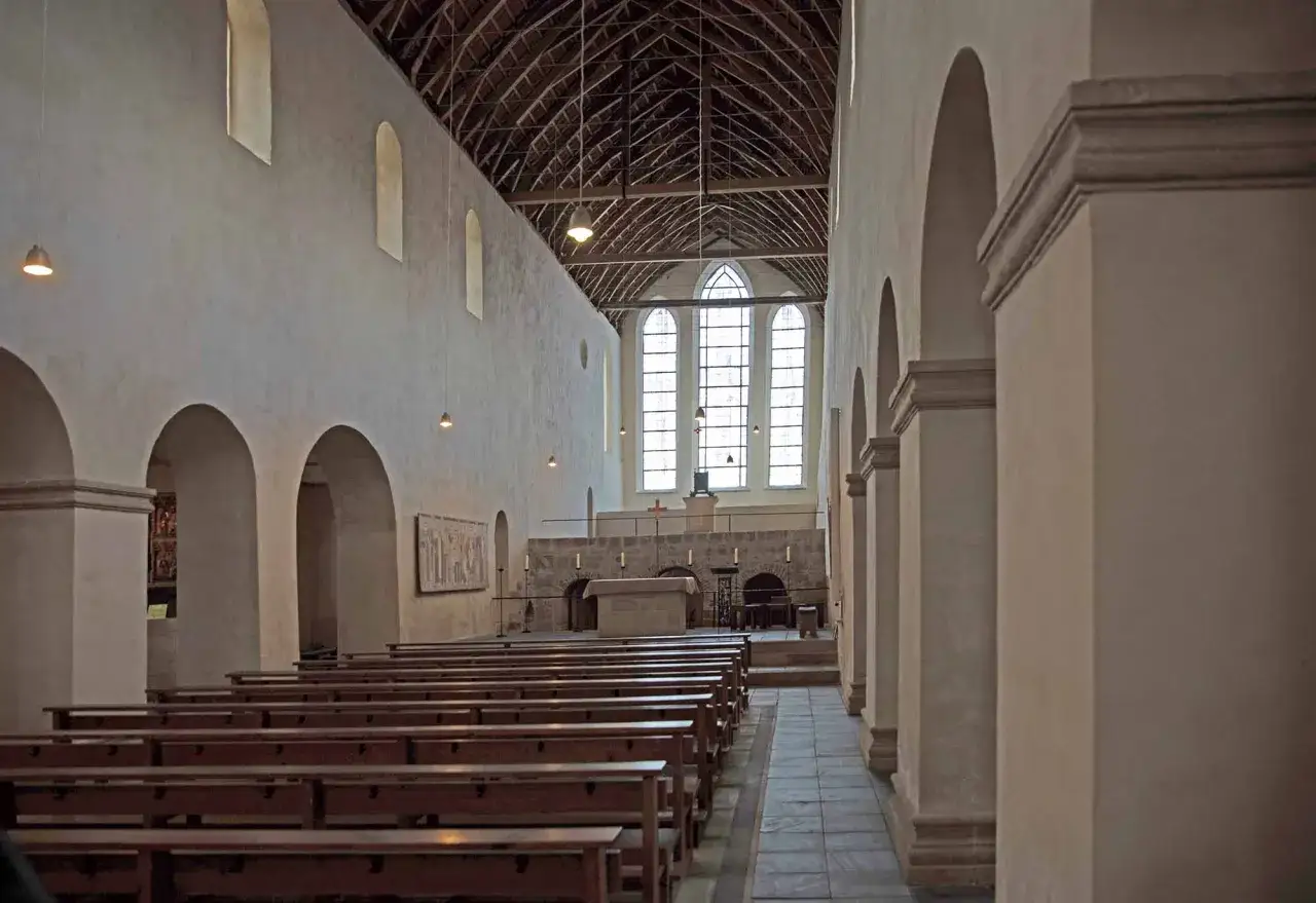Im Inneren einer Kirche mit Holzb&auml;nken und einem Altar. Die Frage 
