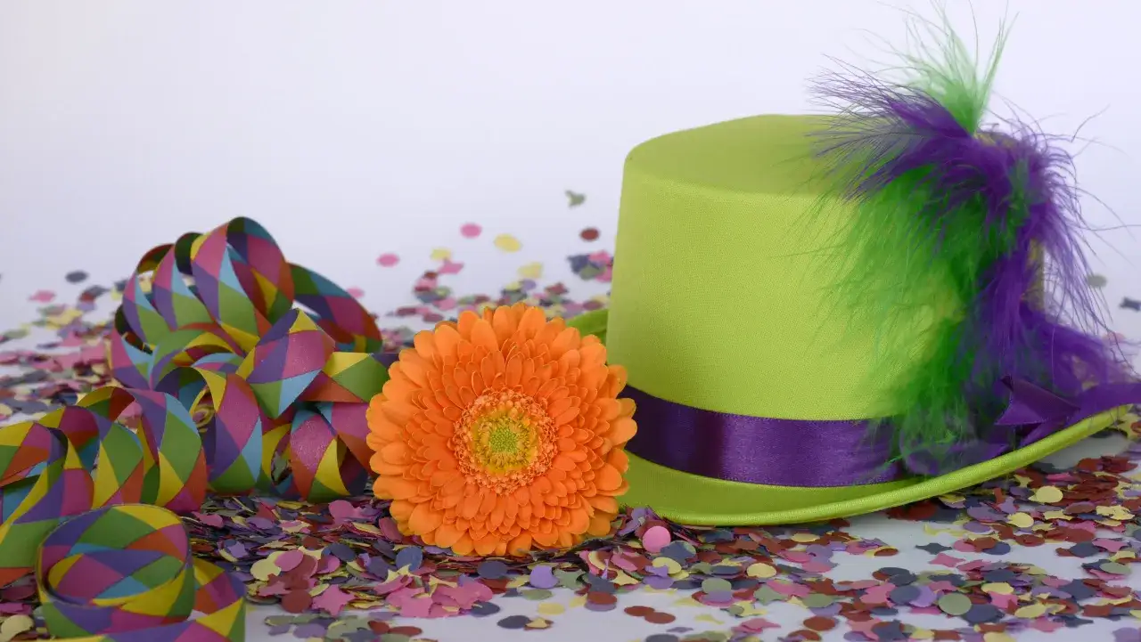 Karneval, Religion und ein bunter Hut: Was hat Karneval mit Religion zu tun? Bunte Girlanden, Konfetti und eine Gerbera.