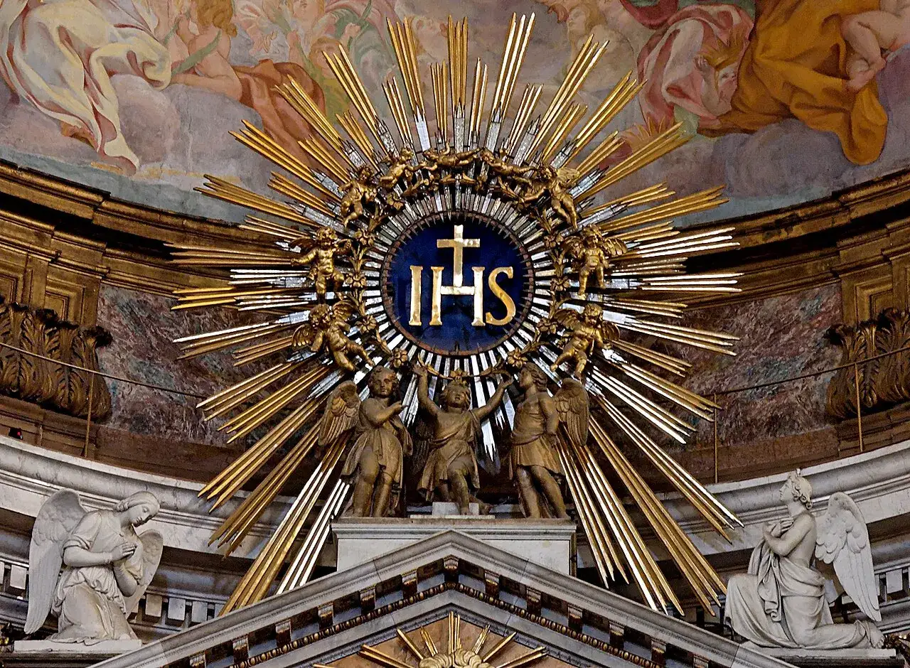 Goldene Strahlenkrone mit IHS-Monogramm und Engeln. Die IHS bedeutung ist hier als Symbol der göttlichen Gegenwart dargestellt.