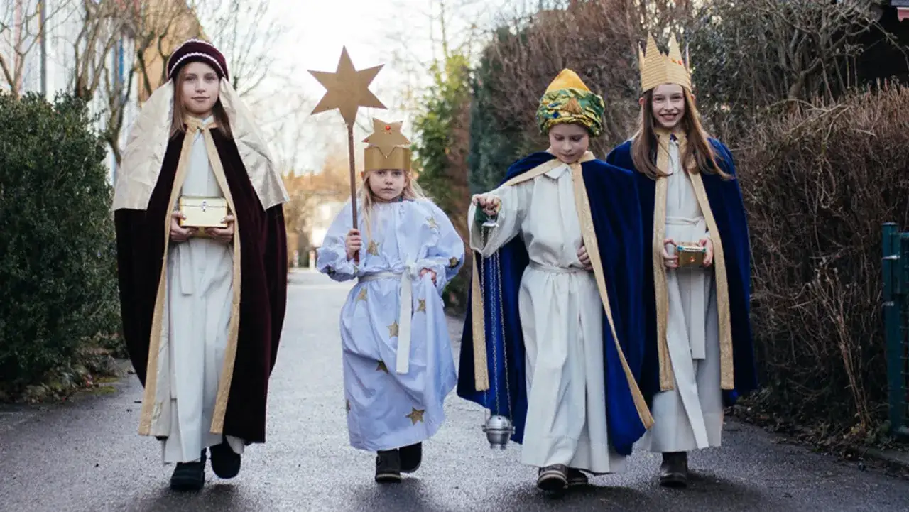Vier Kinder als Caspar, Melchior, Balthasar und ein Sternenkind ziehen mit Gaben und Stern.