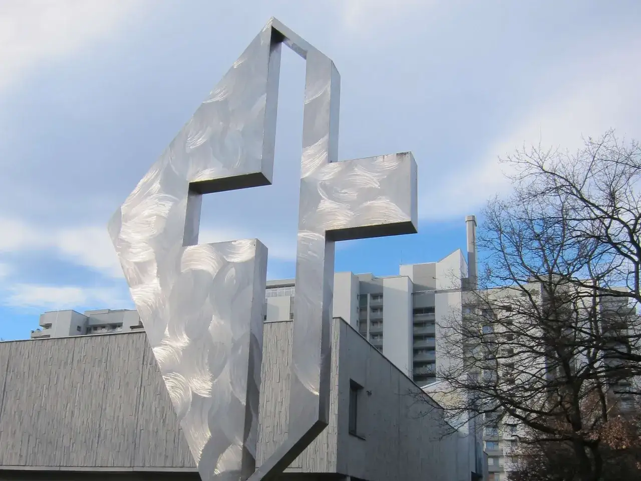 Modernes Kreuz aus Edelstahl vor der Kirche St. Lukas Westkreuz.