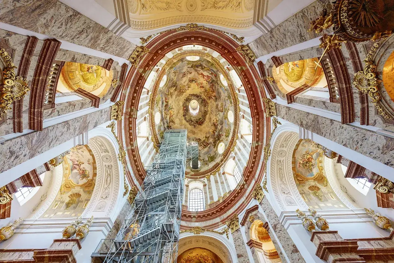 Prunkvolle Deckenmalerei und Marmor in der Karlskirche Wien, mit einem Gerüst, das den Blick auf die Kuppel freigibt.