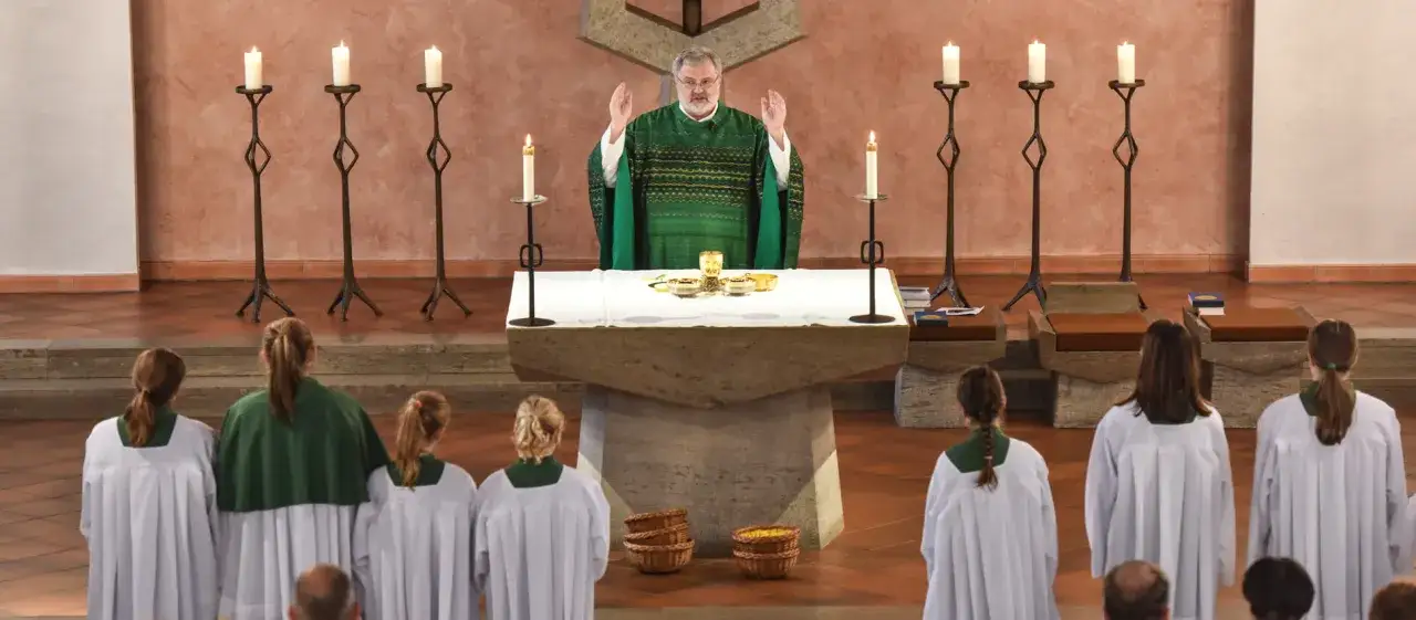Ein Priester feiert die Messe, umgeben von Kerzenlicht und Ministranten. Das Geheimnis des Glaubens wird in dieser heiligen Zeremonie offenbart.