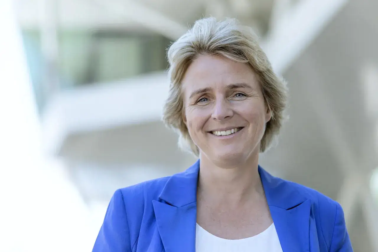 Melanie Wolfers lächelt freundlich in die Kamera, trägt einen blauen Blazer und hat blonde Haare.