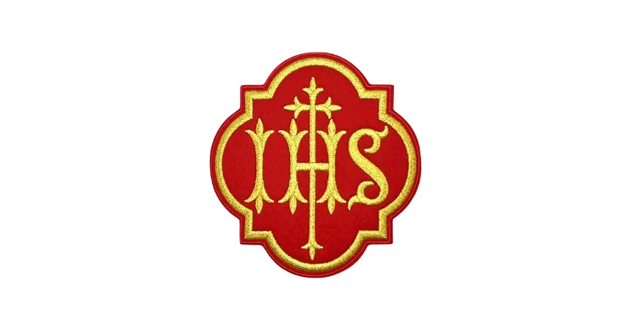 Ein goldenes IHS-Symbol auf rotem Grund, die Farbe kardinalrot leuchtet.