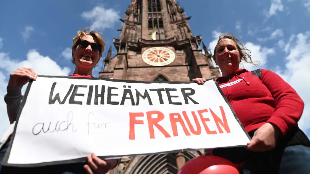 Zwei Frauen halten ein Schild mit der Aufschrift 