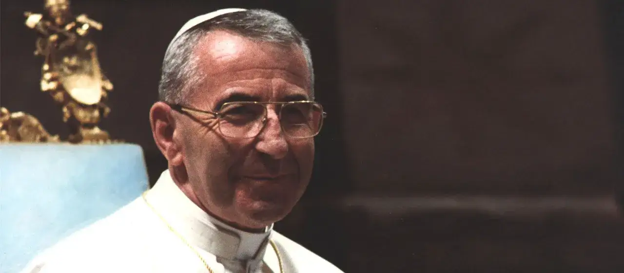 Portr&auml;t von Papst Johannes Paul I. mit Brille und Soutane. Im Hintergrund eine goldene Statue.