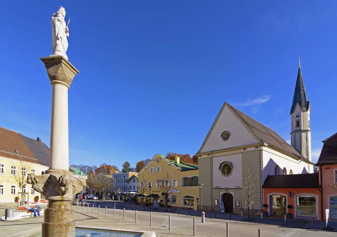 S&auml;ule mit Statue und die Stadtkirche Bad Aibling im sonnigen Ortskern.