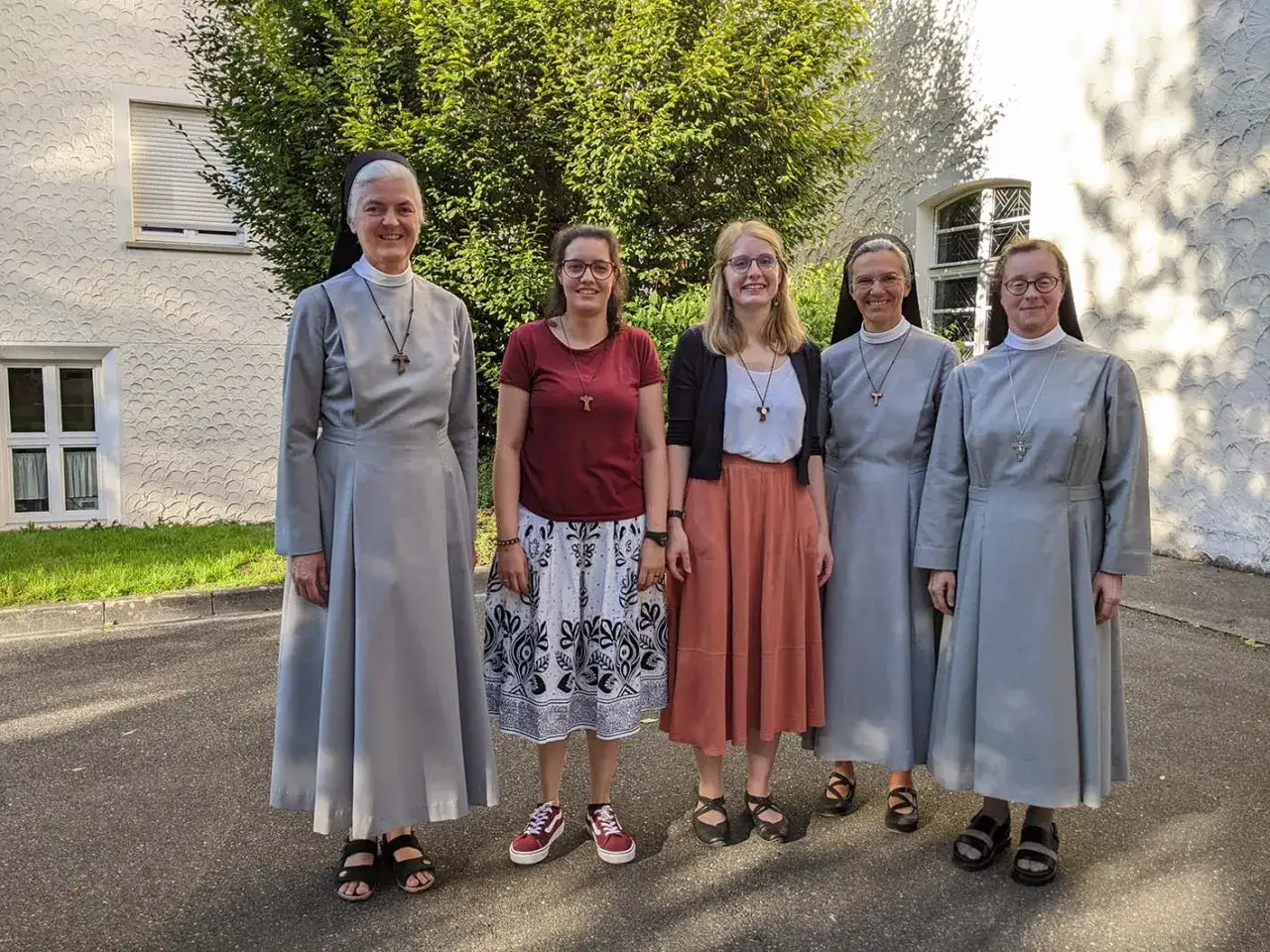 F&uuml;nf Frauen, drei davon Nonnen, stehen vor einem Geb&auml;ude. Vielleicht planen sie, ins Kloster zu gehen.