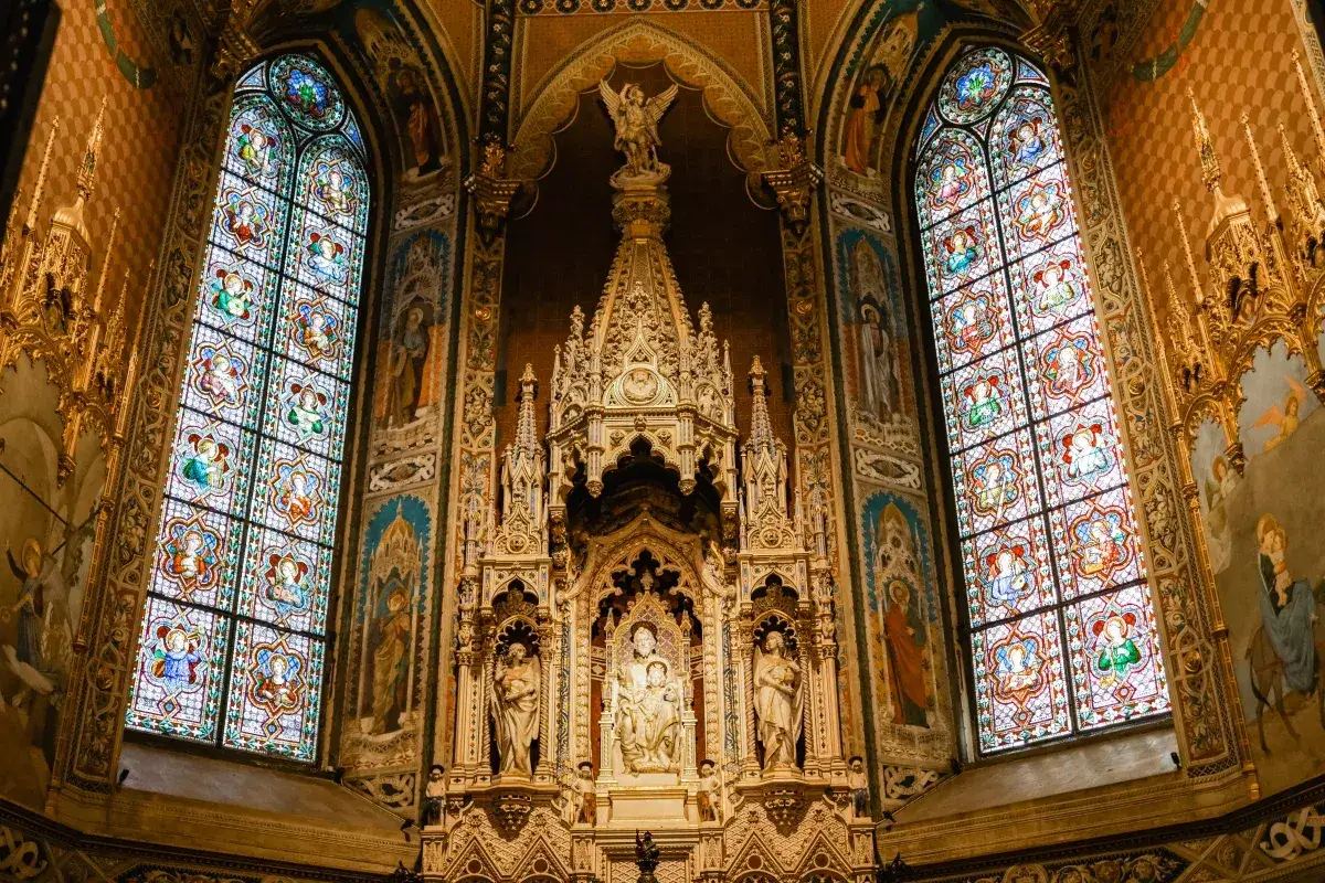 Prunkvoller Altar mit Buntglasfenstern in einer Kirche in Loreto, Italien. Engel und Heilige zieren die W&auml;nde und das kunstvolle Retabel.