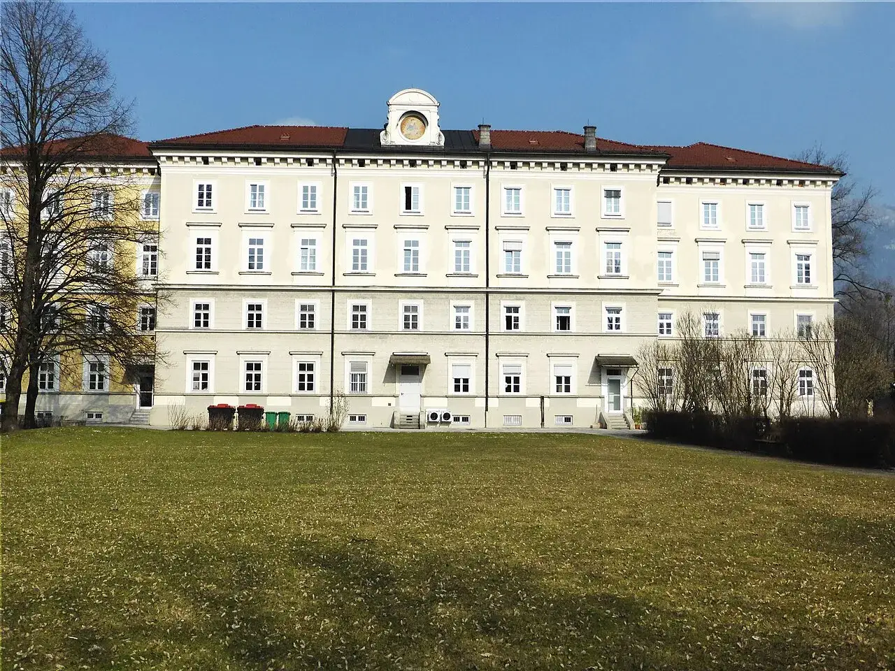 Gro&szlig;es Geb&auml;ude mit vielen Fenstern, das an ein Kloster in Salzburg erinnert. Ein gepflegter Rasen davor.