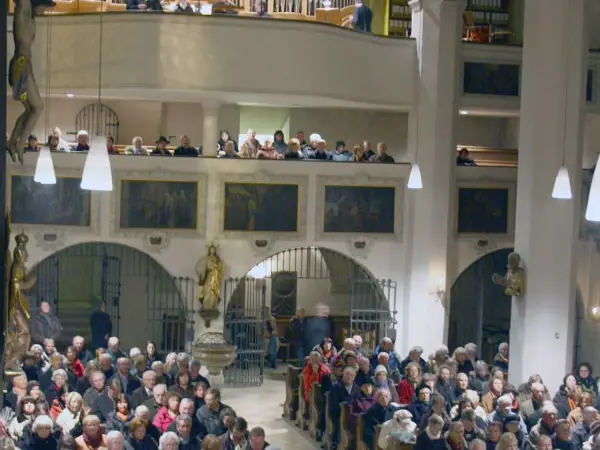 Menschen in der Stadtkirche Wolfratshausen, einige auf der Empore, andere im Kirchenschiff.